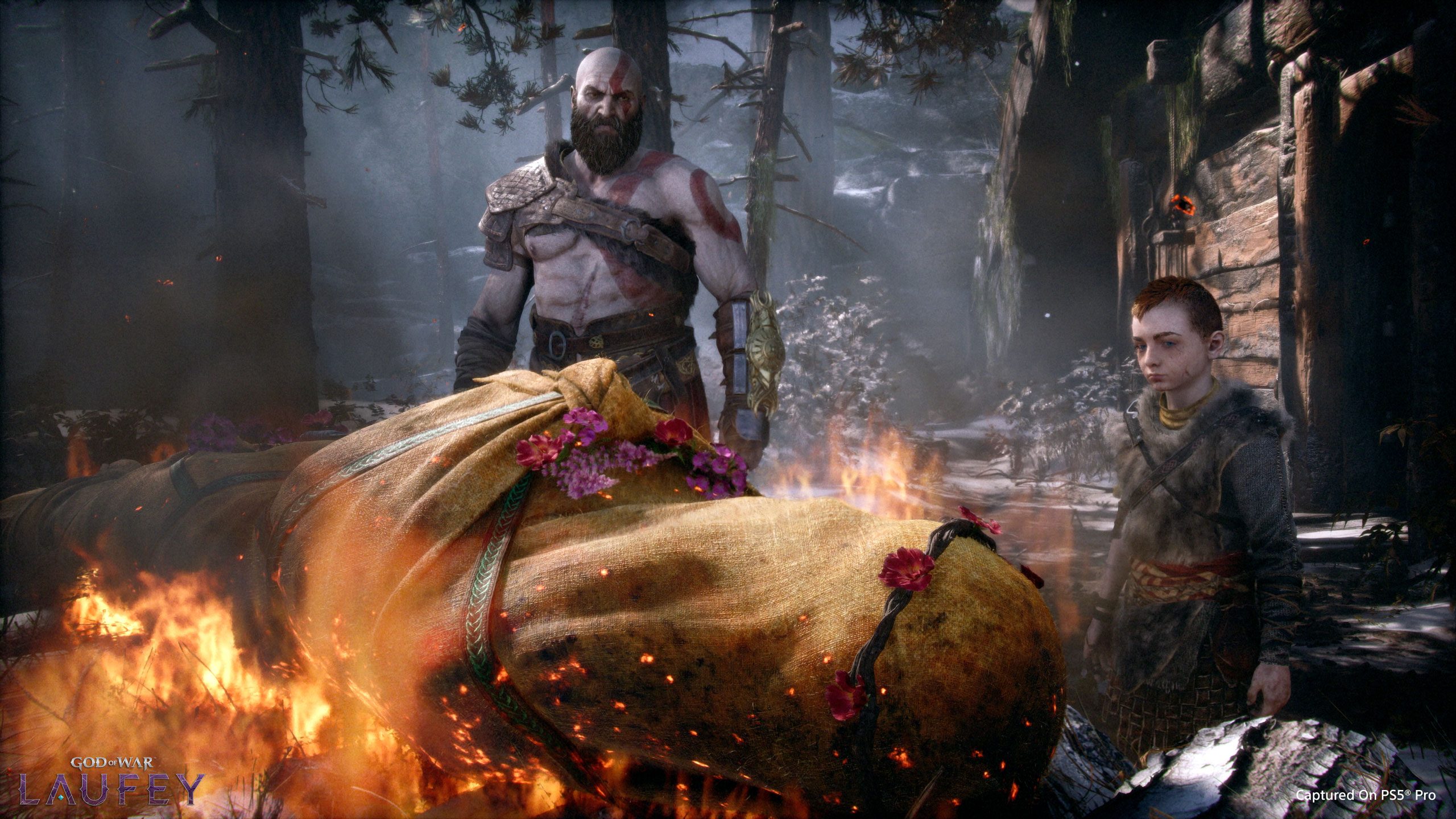 Kratos and Atreus standing over Faye’s burning funeral shroud in the snowy woods, the opening scene of God of War (2018)